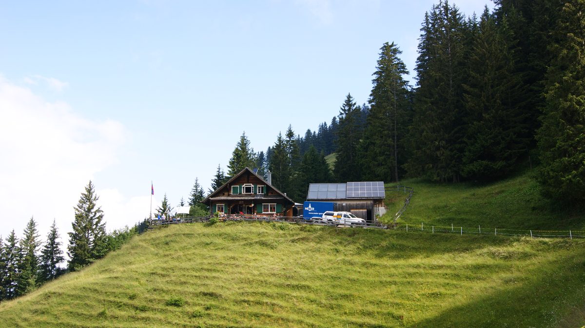 The Gafadurahütte, a Liechtenstein Alpine Club hut above Planken, on a green meadow below spruce forest